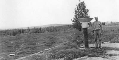 Svartvit bild. Man vid stålbehållare. Nederbördsmätning Svedåsen Hälsingland 1913.