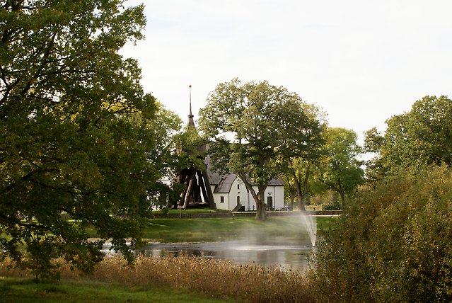 Kyrka omgiven av vatten och natur.