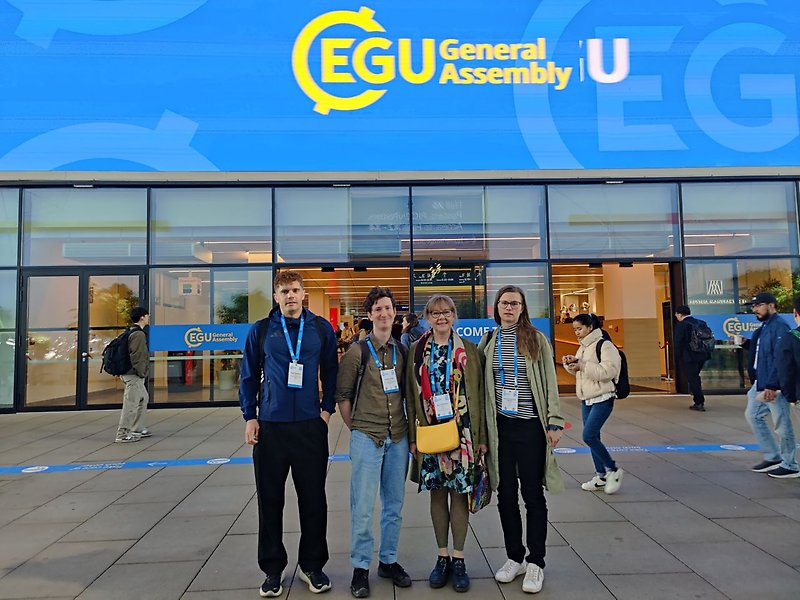 Four researchers standing in front of the entrance to the EGU conference venue. 