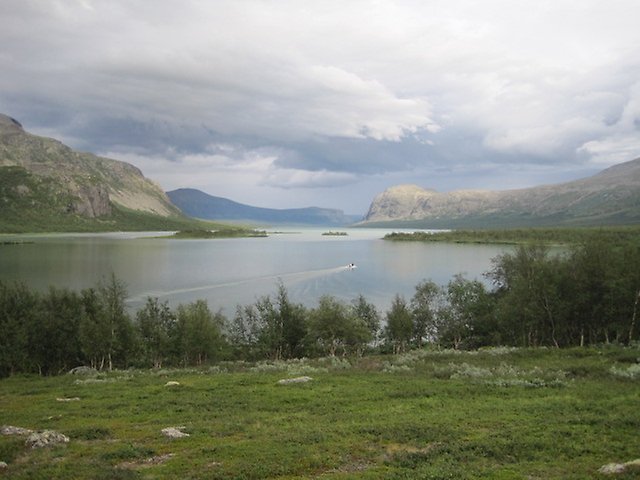 Sjö i Sarek med låglänt vegetation och höga, kala berg omkring, disigt väder. 