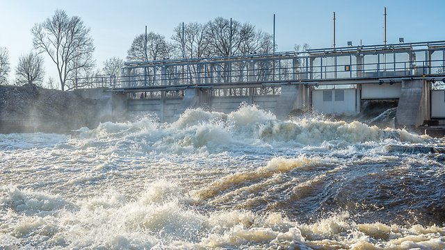Vatten som forsar ur öppen dammlucka i en vattenkraftsdamm. 