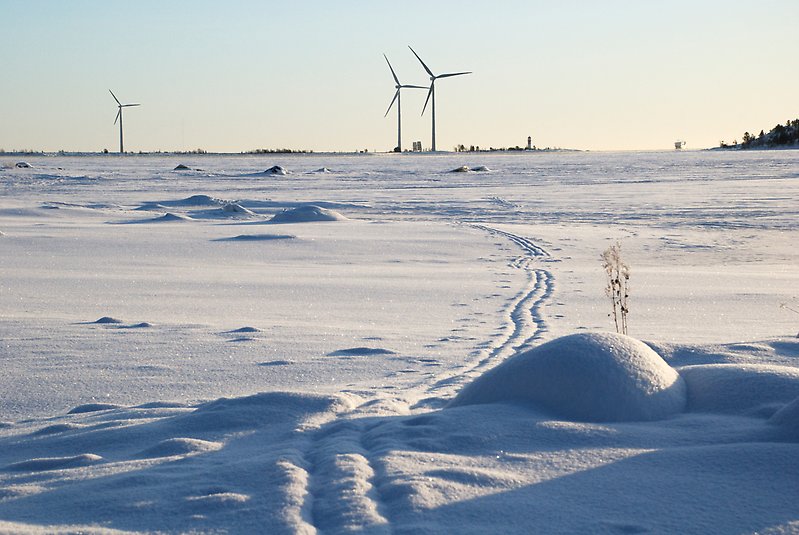 Vindkraftverk i havsmiljö vintertid. Snö, is i solsken.