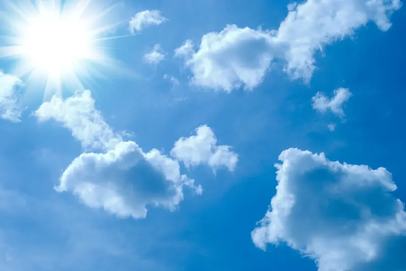 Små vita moln sedda underifrån mot en bakgrund av en blå himmel och solen. 