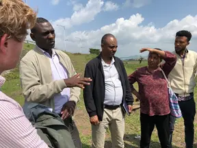 A group of people are standing and discussing outdoors.