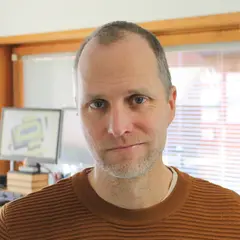 Magnus Asp med sin kontorsarbetsplats i bakgrunden.